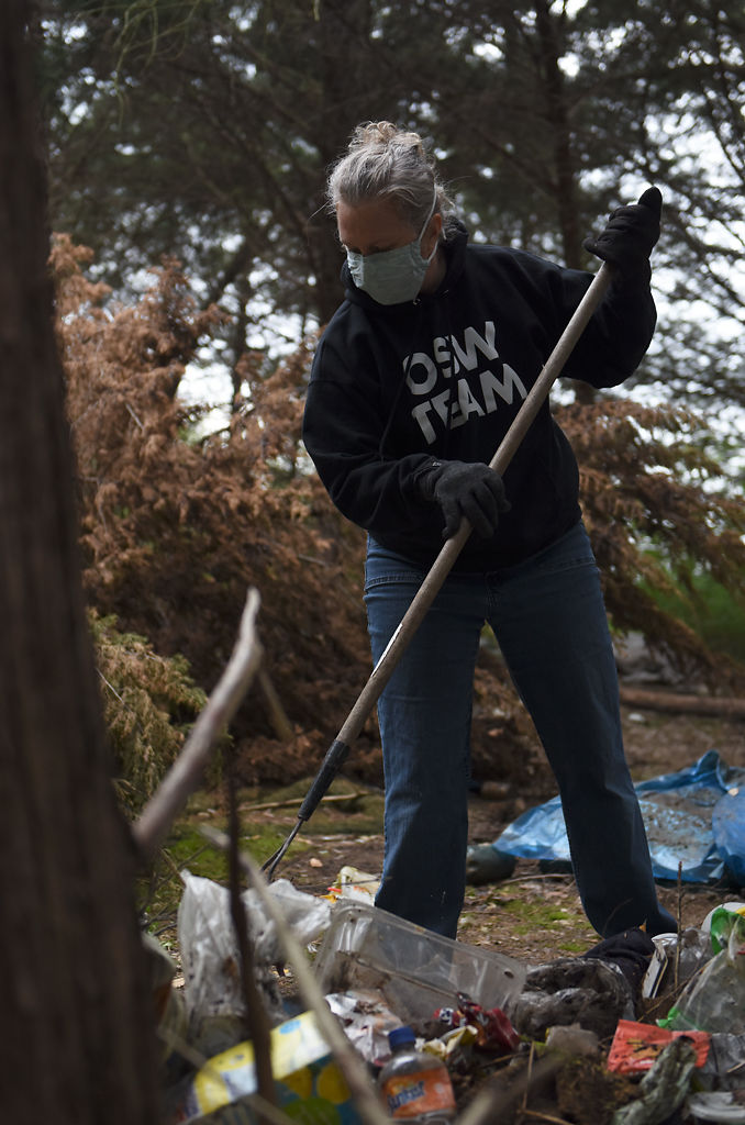 Community volunteer Dawn Finney rakes a pile of garbage